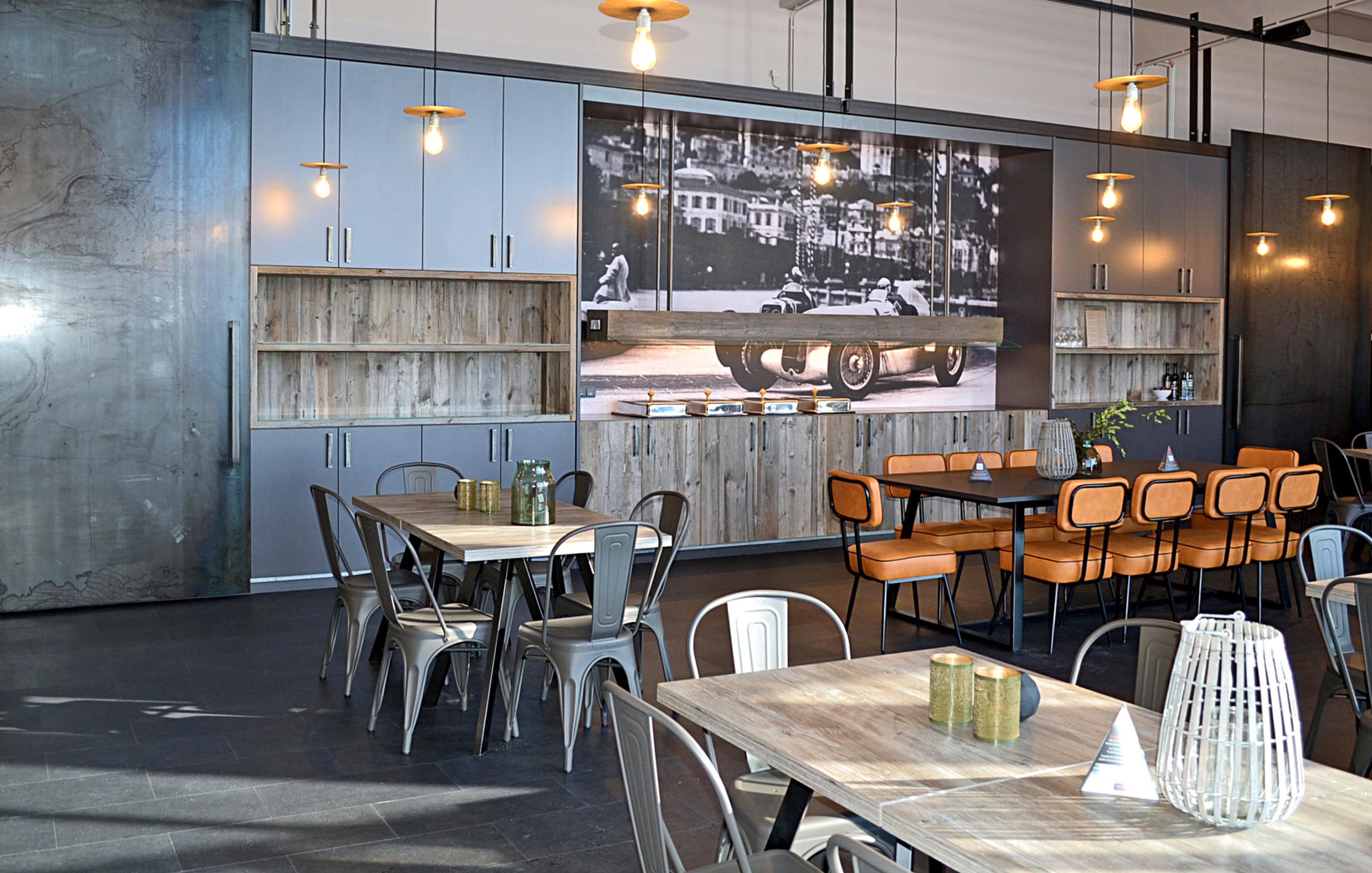 Essbereich mit industriellen Elementen und historischem Motorsport-Bild als Wanddeko.