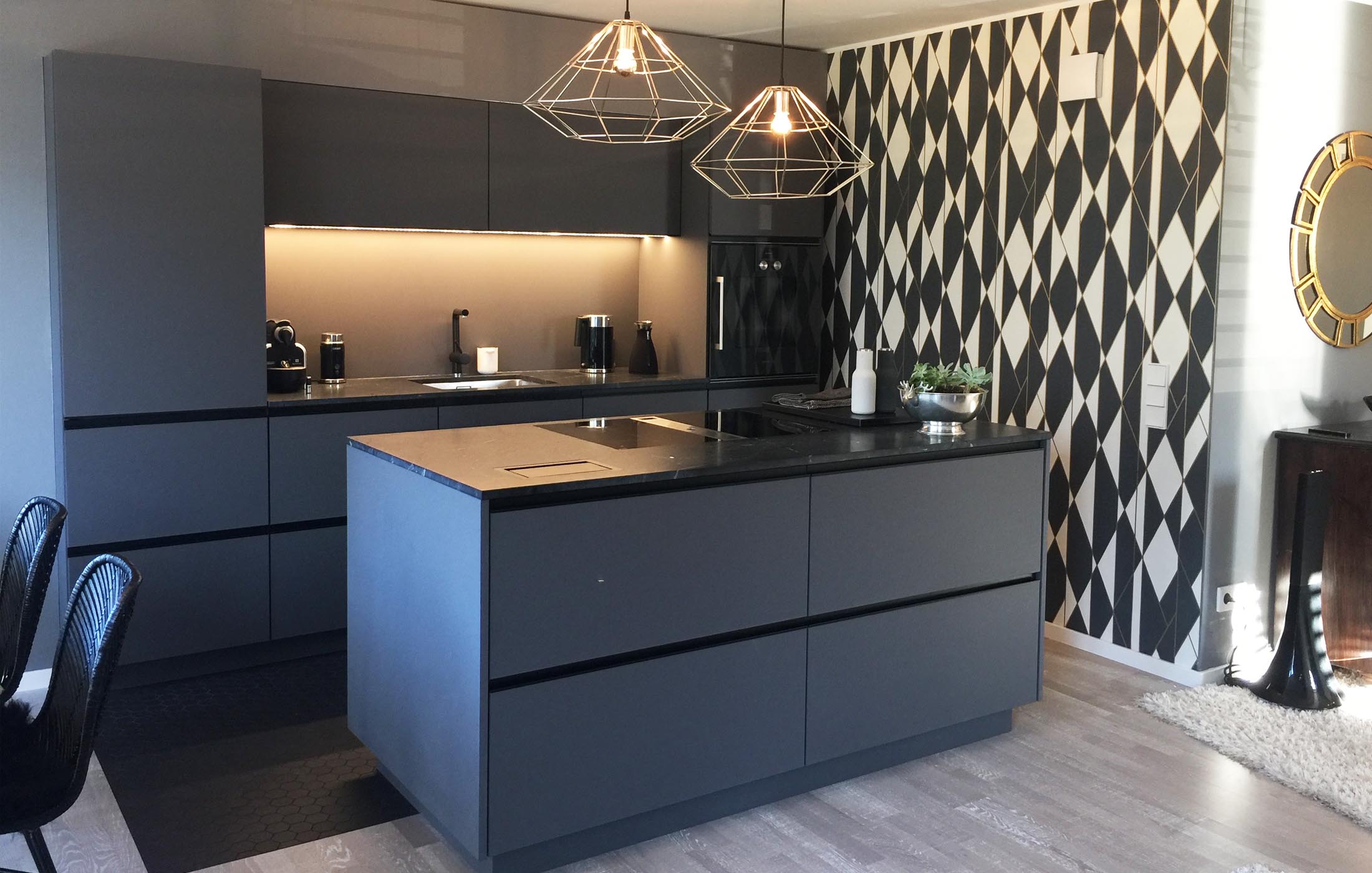 Elegante, graue Küche mit schwarz-weißer Rautentapete und modernen Drahtlampen über der Kochinsel.