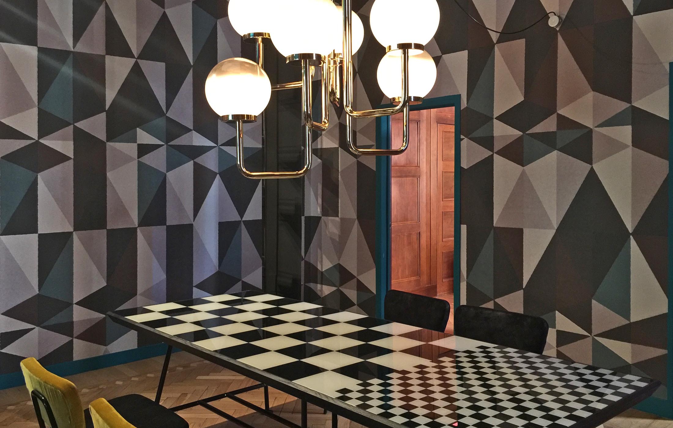 Ein kreatives Esszimmer mit auffälligem schwarz-weißem Schachbrett-Tisch und geometrisch gemusterter Wand.