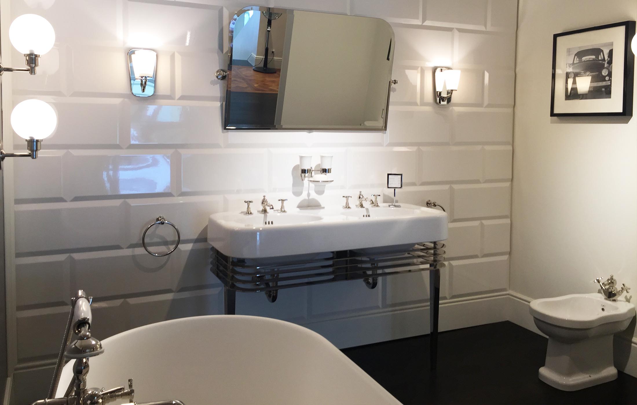 Ein elegantes Bad mit weißem Doppelwaschbecken, Wandlampen, freistehender Wanne und glänzenden Armaturen.