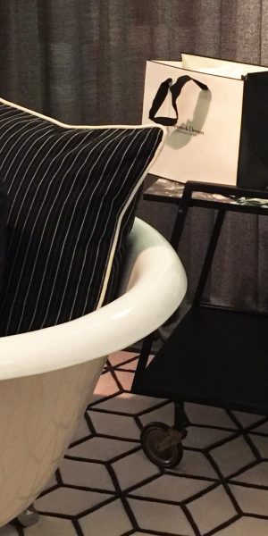 Sessel mit gemusterten Kissen neben stilvollem Barwagen auf geometrischem Teppich