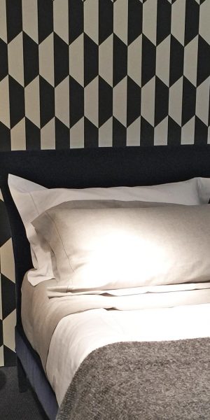 Modernes Schlafzimmer mit grafischer Schwarz-Weiß-Tapete und schlichtem Bett mit grauer Bettwäsche.