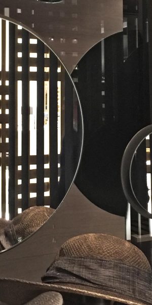 Runde Wandspiegel reflektieren einen stilvoll dekorierten Raum mit Hüten im Vordergrund.