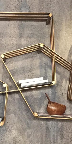 Abstraktes Regal aus dünnen Metallstreben in geometrischer Anordnung mit einzelnen Büchern und Objekten.