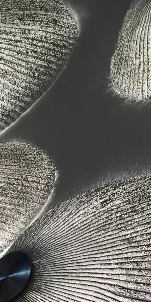 Vier halbrunde Wandlampen mit texturierter Oberfläche werfen ein sanftes Licht an die Wand.