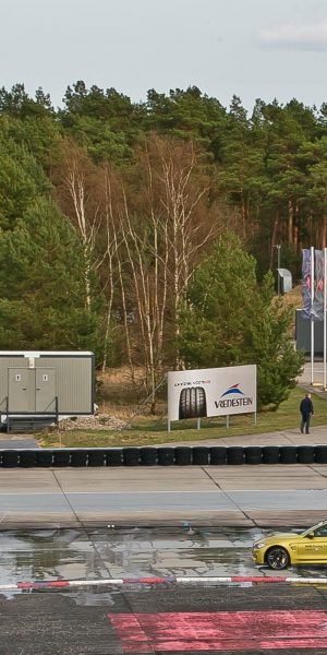 Blick auf das Driving Center Groß Dölln mit geparkten Fahrzeugen und Teststrecke im Vordergrund.