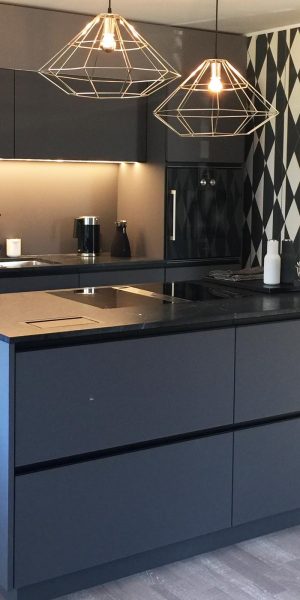 Elegante, graue Küche mit schwarz-weißer Rautentapete und modernen Drahtlampen über der Kochinsel.