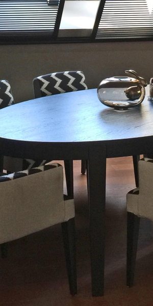 Essbereich mit ovalem Tisch und gemusterten Stühlen unter Dachschräge.