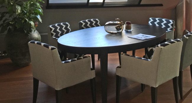 Essbereich mit ovalem Tisch und gemusterten Stühlen unter Dachschräge.